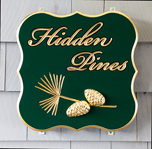 Hidden Pines carved sign with carved pine cones and needles