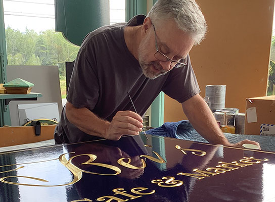 kevin Freeman working on a custom sign holding a paint brush